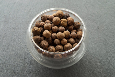 Allspice close-up. Glass bowl. Dark natural stone backgroundの写真素材