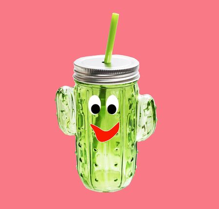Bottle in the form of a cactus with a muzzle on a pink background.の写真素材