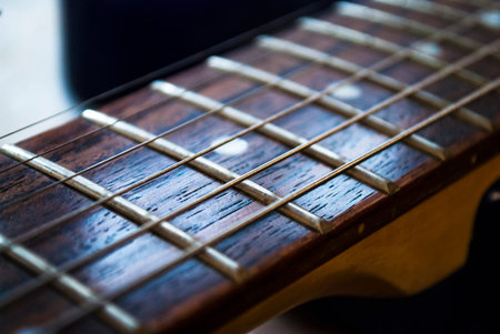 Guitar strings on a wooden neck closeup.