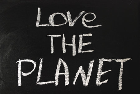 Word love the planet written in white chalk on a black chalkboard.