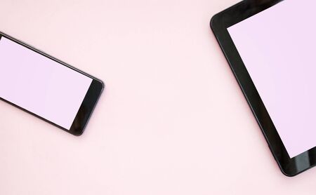 Black mobile phone, black tablet, on a pink background. Work in the office. Top view. Flat lay. Copy space. Mock upの写真素材