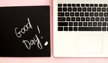 Black and white laptop keyboard, black chalk board with chalk inscription Good day, pink background. Top view. Flat lay. Copy space.の写真素材