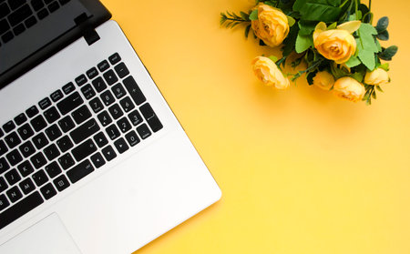 Black-white laptop keyboard, yellow flowers on an orange background. Flat lay. Top view. Copy spaceの写真素材