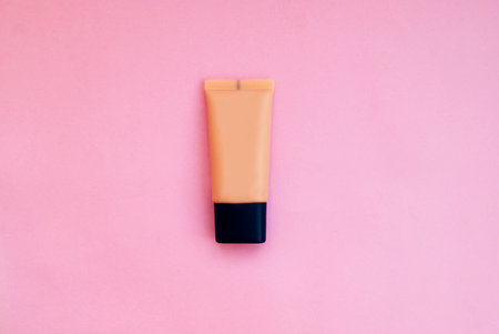 Beige flat bottle of foundation on a pink background. Flat lay. Top view.