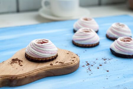 Cake, white-pink marshmallows, jam, cookies, chocolate on a wooden, blue background. Close-up.の写真素材