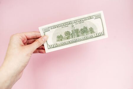 bill in hand on a pink background. 100 dollars. Money.の写真素材