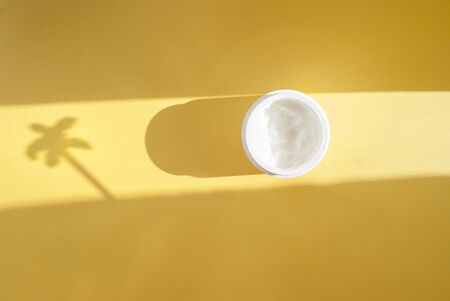 Bottle of white cosmetic on a yellow background, hard shadow. Place waiting for text. Flat lay.の写真素材