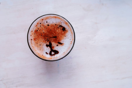Glass of latte with foam close-up on a white background. Top view. Place for text