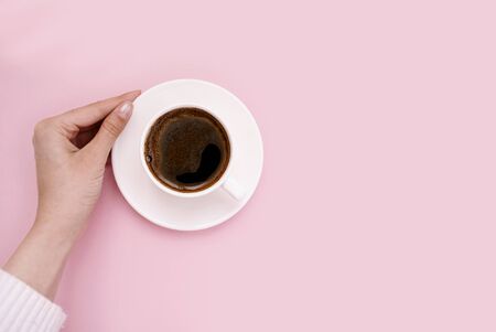 White cup of coffee in hand on a pink background. Place for text. Good morning. Top view. Flat lay.の写真素材