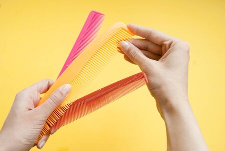 Set of multi-colored hairbrushes for hair on a yellow backgroundの写真素材