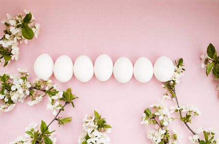 White easter eggs, white spring flowers on a pink background. Happy Easter. Place for text. Top view. Flat layの写真素材
