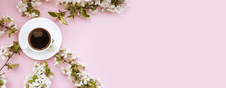 White cup and saucer of brewed coffee, spring flowers on a pink background. Place for text. Romantic mood. Card. The beginning of spring. Flat lay. Bannerの写真素材