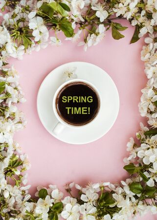 Frame of white spring flowers on a pink background, white cup of coffee. The beginning of spring. Romantic mood. flat layの写真素材