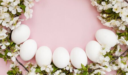 White easter eggs, white spring flowers on a pink background. Happy Easter. Place for text. Top view. Flat layの写真素材