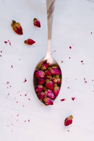 Dried tea rose buds in a spoon on a light background, Close-up.の写真素材