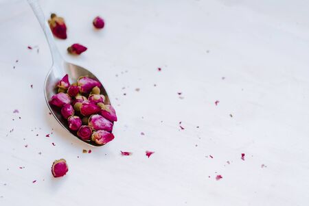 Dried tea rose buds in a spoon on a light background, Close-up.の写真素材