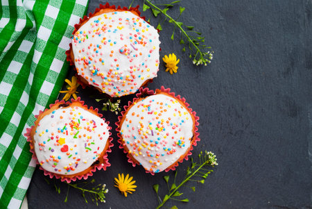 Three homemade cupcakes on a gray board decorated with flowers