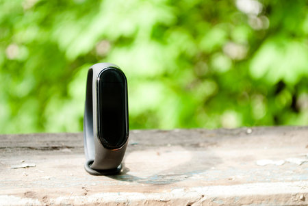 Black fitness bracelet on a background of nature. Place for text