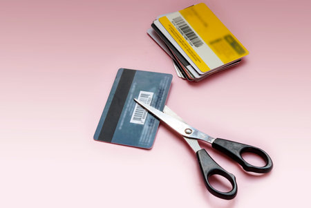 credit and discount cards cut with scissors on a pink background.