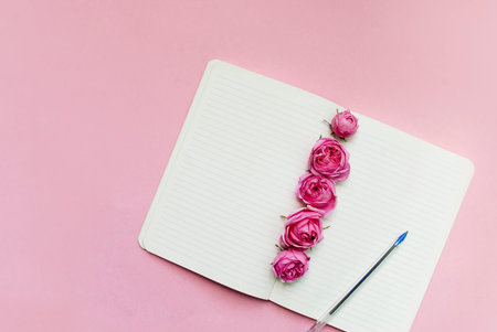 Open notebook, flowers pink background. Mock up. Postcard template. Place for text