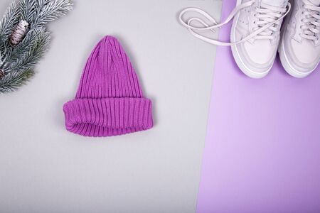 One knitted pink hat with Christmas tree branch and modern pink shoes. Fashion flat lay composition on gray and pink background. Layout and with copy spaceの写真素材
