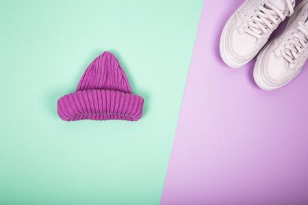 One knitted purple hat and modern pink sneakers. Flat lay composition on turquoise and pink background. Layout and with copy spaceの写真素材