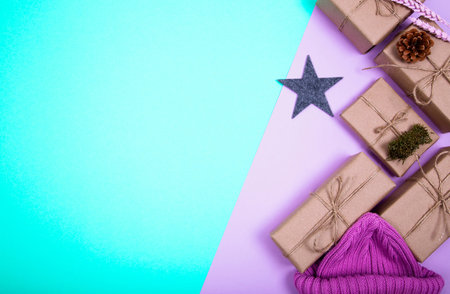 Classy Christmas gifts box presents and knitted cap on a colored paper background. Flat lat winter...