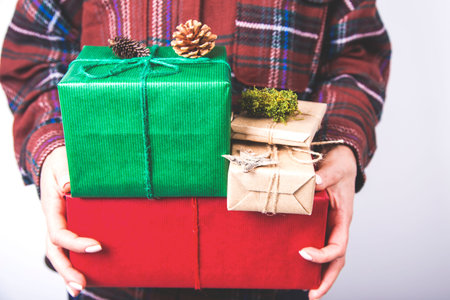 Female hands with beautiful manicure holding pile of gifts in different colors with ribbons and...