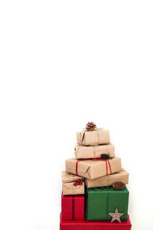 A pile of Christmas gifts in red, green and natural wrapping with ribbons and decorations. Isolated on white backgroundの写真素材
