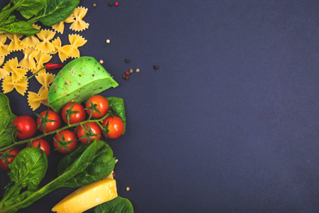 Italian food background with vine tomatoes, basil, spaghetti, spinach, parmesan, peppercorns,...