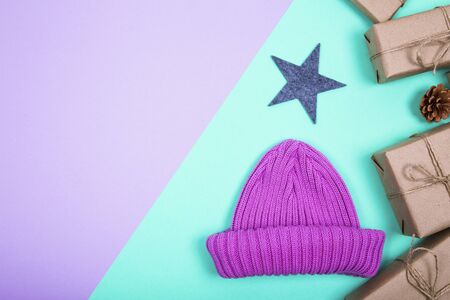 Classy Christmas gifts box presents and knitted cap on a colored paper background. Flat lat winter composition. Top view and copy spaceの写真素材