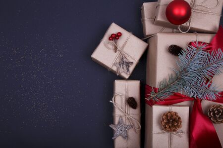 Christmas composition. Christmas gift, pine cones, fir branches, glitter on black background. Flat lay, top view, copy spaceの写真素材