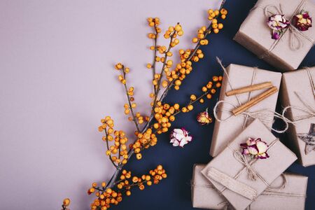 Gift boxes with dry roses and branch of sea buckthorn on a black and beige backgroundの写真素材