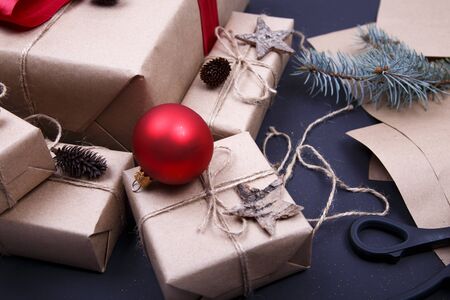 Christmas composition. Hand made Christmas gifts, pine cones, fir branches, wrapped paper and scissors on black background. Flat lay, top view, copy spaceの写真素材