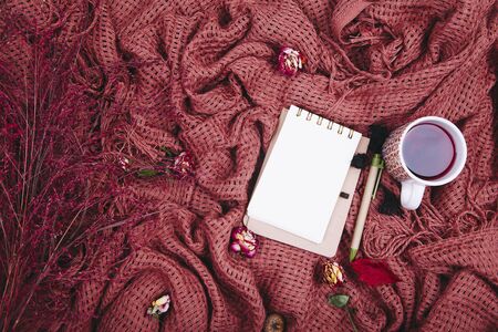 Autumn composition. Cup of tae, blanket, notebook with pen, dried roses. Flat lay, top view, copy spaceの写真素材