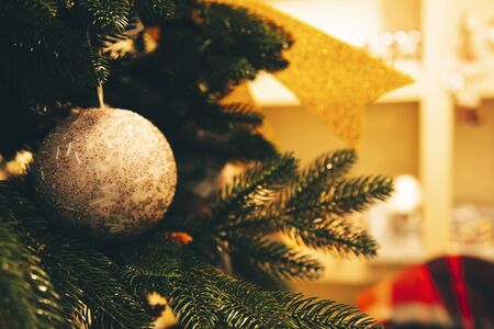 Shiny Christmas ball hanging on pine branches with festive backgroundの写真素材