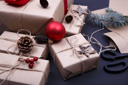Christmas composition. Hand made Christmas gifts, pine cones, fir branches, wrapped paper and scissors on black background.の写真素材