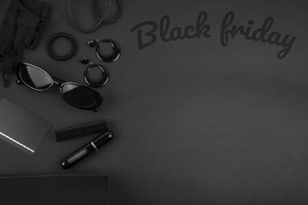 Black monochromatic flatlay on black background. Accessories and beauty equipment. Black friday sale concept. Space for textの写真素材