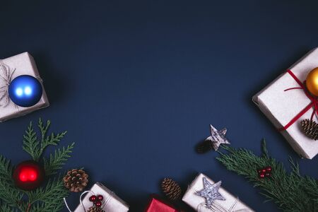 Christmas composition. Christmas gift, pine cones, fir branches with decoration on dark blue background. Flat lay, top view, copy spaceの写真素材