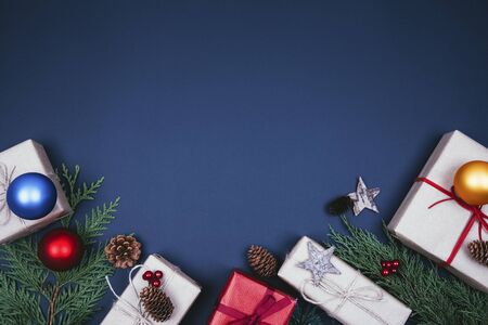 Christmas composition. Christmas gift, pine cones, fir branches with decoration on dark blue background. Flat lay, top view, copy spaceの写真素材
