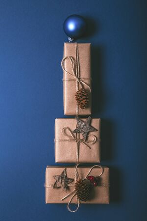 Christmas gift boxes with decoration laid out in the shape of a Christmas tree on blue background, overhead view.の写真素材