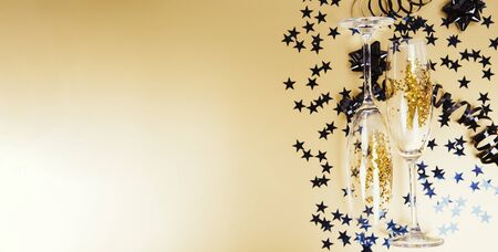 New years eve celebration background with champagne glasses and sparkles on golden background. Bannerの写真素材