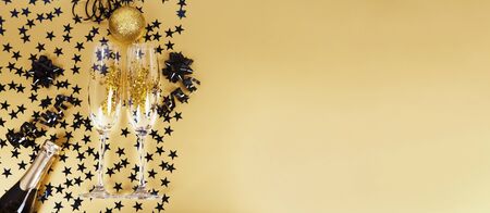 New years eve celebration background with bottle of champagne and glasses and decorations on golden background. Bannerの写真素材