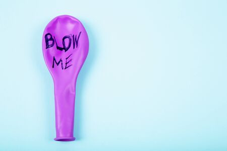 Pink rubber unblown balloons on a light blue background. With note blow me.の写真素材