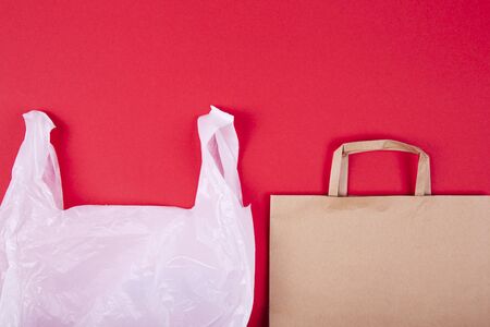 Disposable plastic bag and paper bag on red background. Zero waste concept. Space for textの写真素材