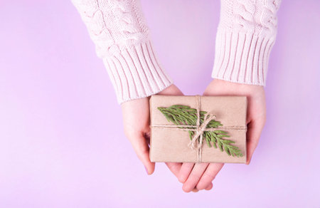 Woman's hands holding craft paper gift box with as a present for Christmas, new year, valentine day...