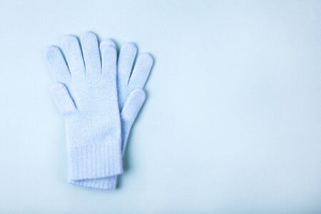 Warm woolen knitted blue gloves on color backgroundの写真素材