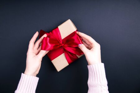 Close up on female hands making a gift box for valentine day, birthday, mother's day. Flat lay. Symbol of love.の写真素材