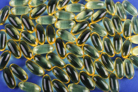 Omega 3. Fish oil capsules on blue background and texture, vitamin D supplement. Close up, high resolution product. Health care conceptの写真素材