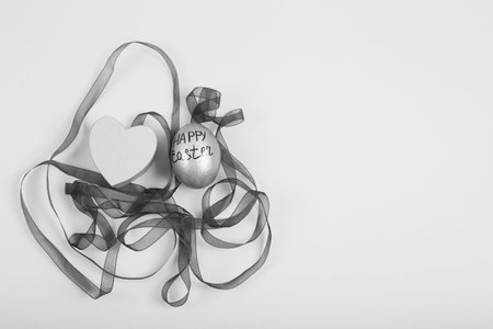 Black and White image. Easter egg with ribbon on a white background. Minimal easter concept. Flat...
